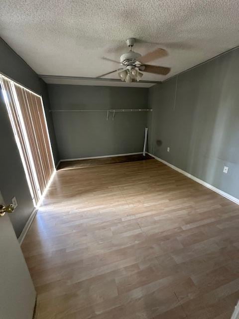 empty room with hardwood / wood-style floors, ceiling fan, and a textured ceiling