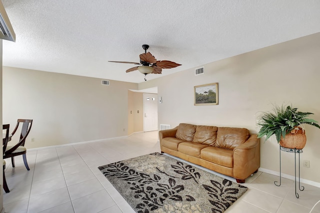 living room featuring ceiling fan, light tile patterned floors, and a textured ceiling