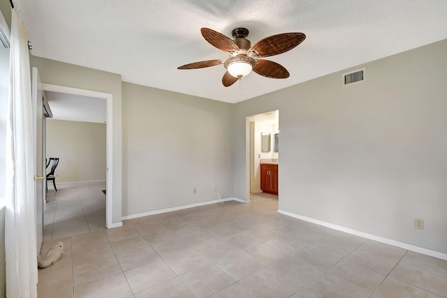 unfurnished bedroom featuring ensuite bathroom, ceiling fan, and light tile patterned flooring