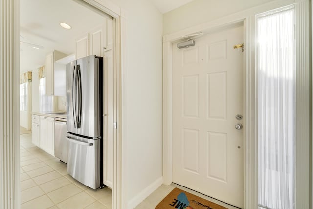 interior space with dishwasher, stainless steel fridge, a wealth of natural light, light tile patterned flooring, and white cabinetry