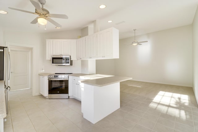 kitchen featuring kitchen peninsula, ceiling fan, light tile patterned floors, appliances with stainless steel finishes, and white cabinetry