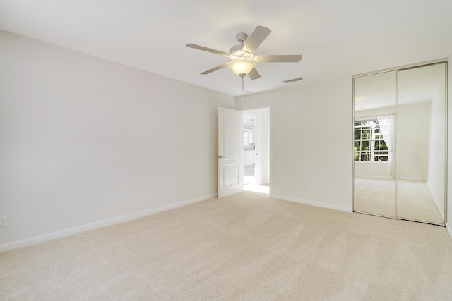 unfurnished bedroom featuring ceiling fan, light colored carpet, and a closet