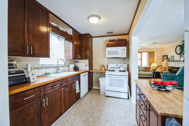 kitchen with white appliances, butcher block countertops, dark brown cabinetry, and sink