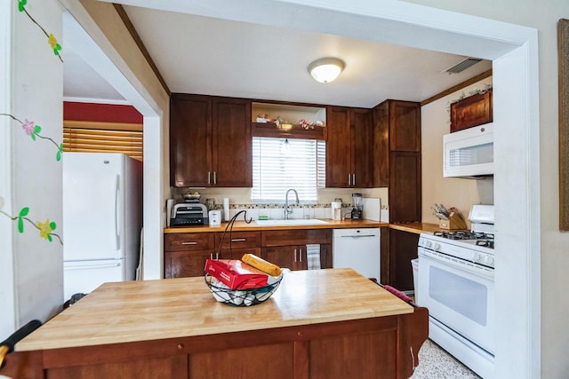 kitchen with dark brown cabinetry, white appliances, sink, and wooden counters