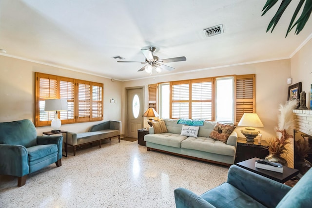 living room with a brick fireplace, a wealth of natural light, crown molding, and ceiling fan