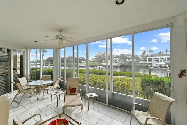 sunroom featuring ceiling fan and a water view