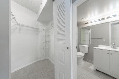 walk in closet with light tile patterned floors and sink