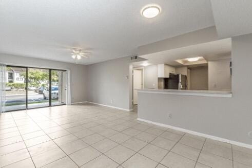 spare room with ceiling fan and light tile patterned floors