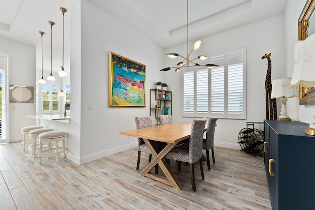 dining room with a chandelier, light hardwood / wood-style floors, and a tray ceiling