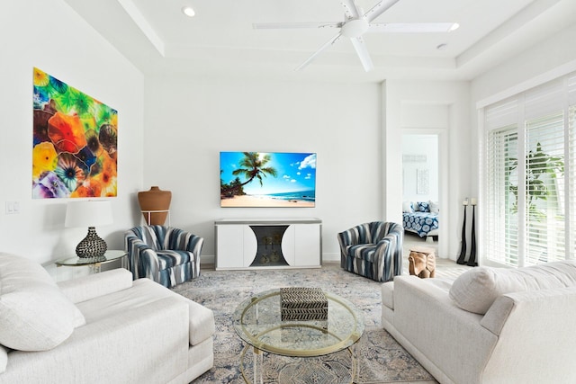 living room featuring a raised ceiling and ceiling fan