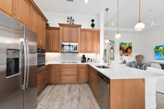 9289 SW Miracoli Way, Port Saint Lucie, FL 34987 - kitchen featuring stainless steel appliances, a sink, a peninsula, light wood-type flooring, and tasteful backsplash