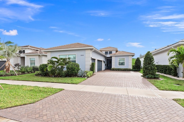 9289 SW Miracoli Way, Port Saint Lucie, FL 34987 - view of front of home with decorative driveway, a garage, stucco siding, a front lawn, and a tiled roof