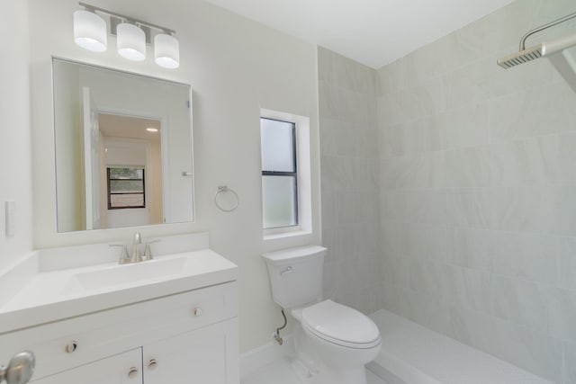 bathroom featuring tiled shower, vanity, and toilet