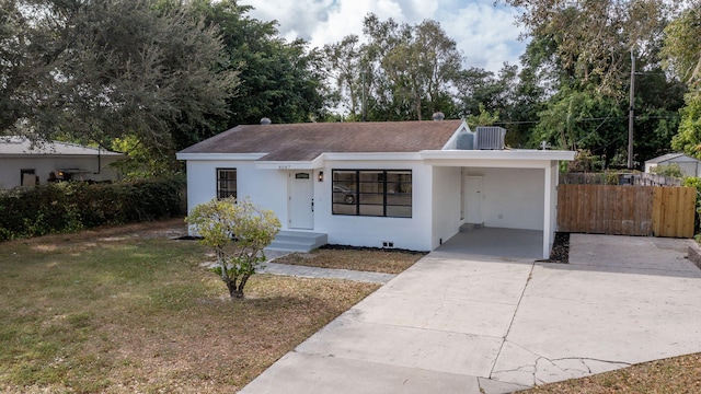 ranch-style house with a front yard, a carport, and cooling unit