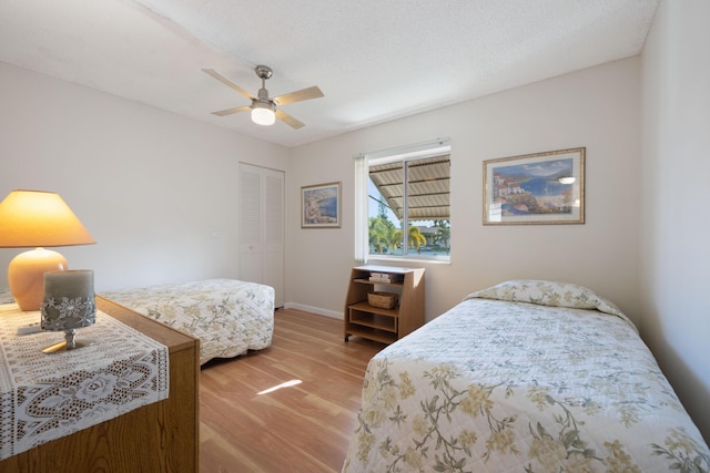 bedroom with ceiling fan, a closet, wood-type flooring, and a textured ceiling