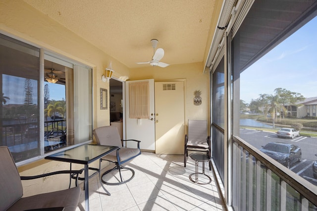 sunroom / solarium with a water view and ceiling fan