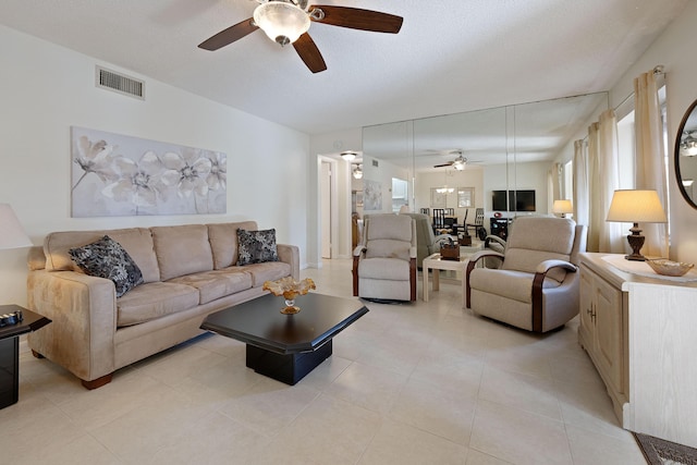 living room with a textured ceiling, ceiling fan, and light tile patterned flooring