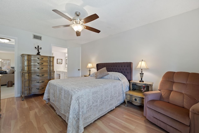 bedroom featuring ceiling fan, light hardwood / wood-style floors, and connected bathroom