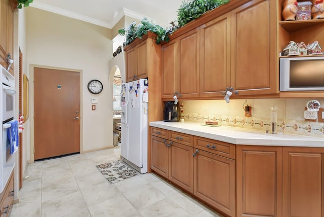 kitchen with decorative backsplash, crown molding, light tile patterned flooring, and white appliances