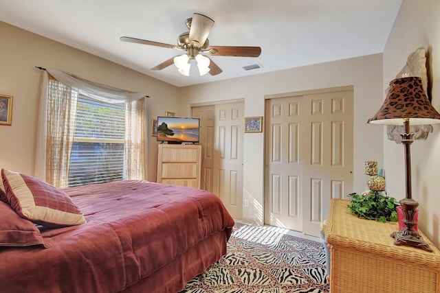 bedroom with ceiling fan and two closets