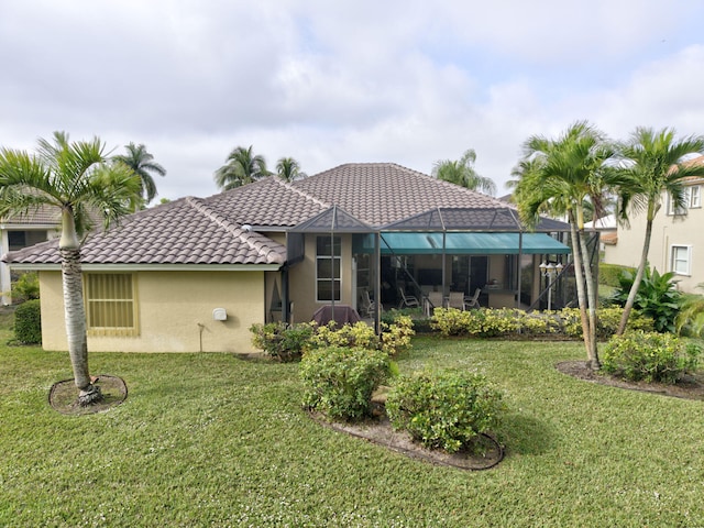 rear view of property with glass enclosure and a lawn