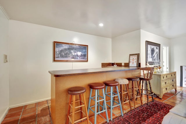 bar with tile patterned floors and green cabinetry