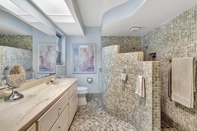 bathroom featuring toilet, vanity, and tiled shower