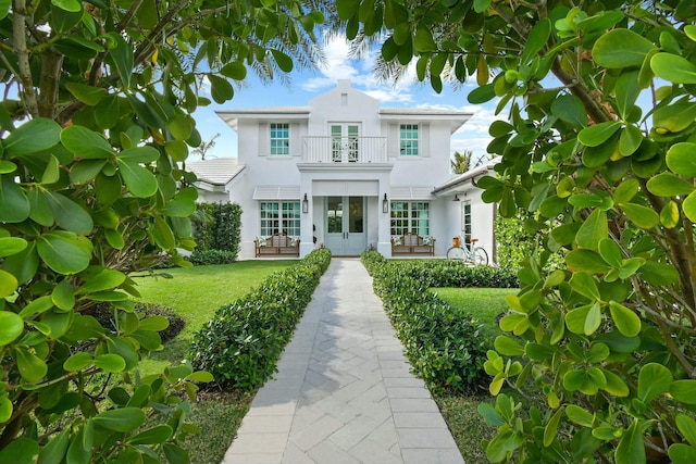 mediterranean / spanish house with a balcony, a front lawn, and french doors