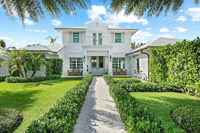 view of front facade featuring a front lawn, french doors, and a balcony