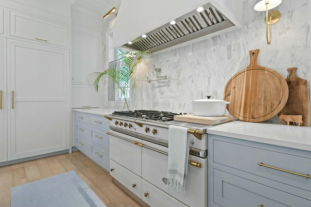 kitchen featuring white cabinets, light hardwood / wood-style flooring, decorative backsplash, and wall chimney exhaust hood