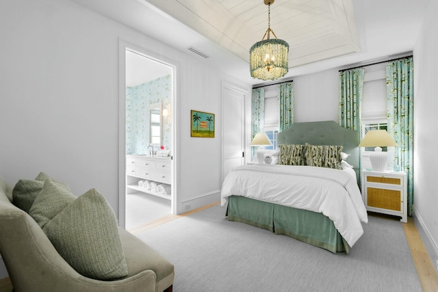 bedroom featuring hardwood / wood-style floors, a chandelier, and a tray ceiling