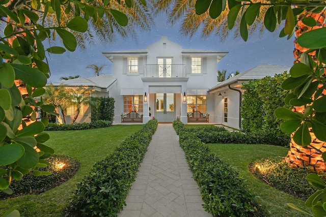 mediterranean / spanish-style home featuring a patio area, a front yard, french doors, and a balcony