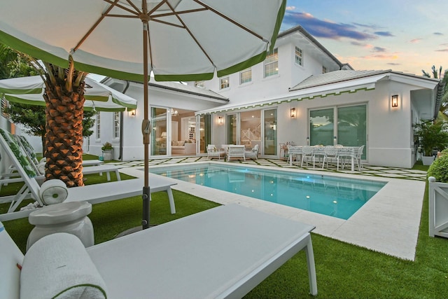 pool at dusk with a patio area