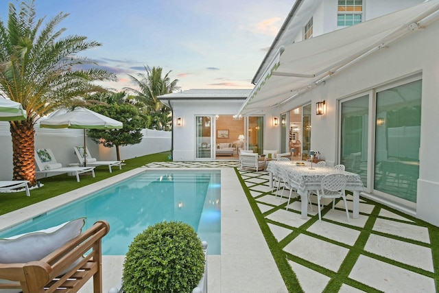 pool at dusk with a patio area