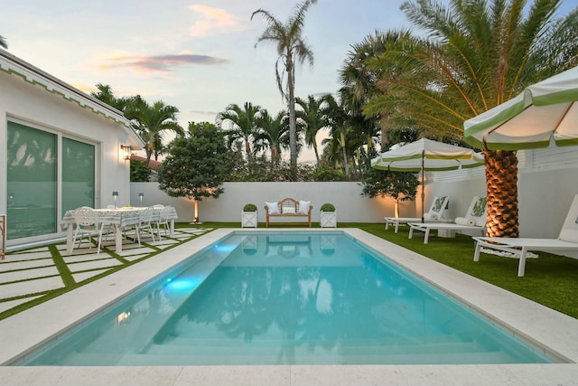 pool at dusk featuring a patio area