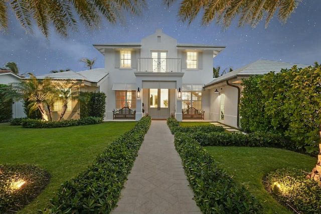 rear view of property featuring a balcony and a yard