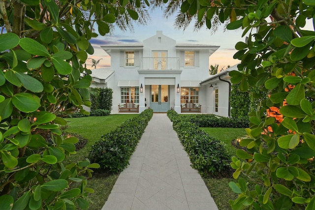 mediterranean / spanish home with a yard, french doors, and a balcony