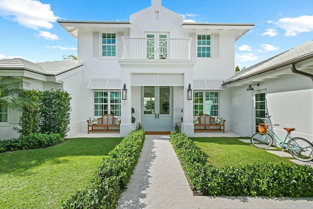 back of house with a balcony and a lawn