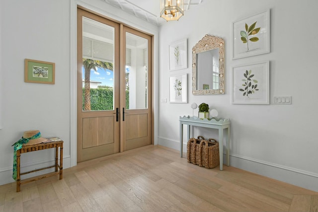 doorway to outside featuring an inviting chandelier, light hardwood / wood-style floors, and french doors