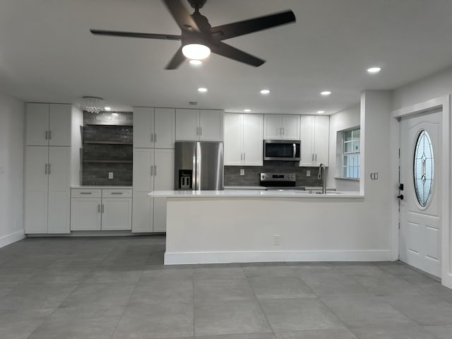 kitchen with tasteful backsplash, white cabinetry, ceiling fan, and stainless steel appliances