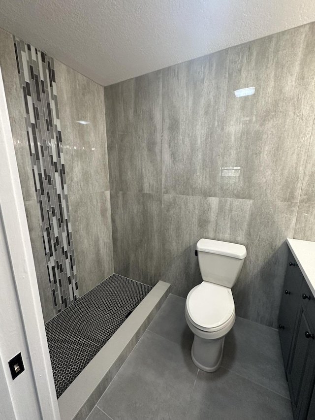 bathroom with vanity, tile patterned floors, toilet, a textured ceiling, and walk in shower