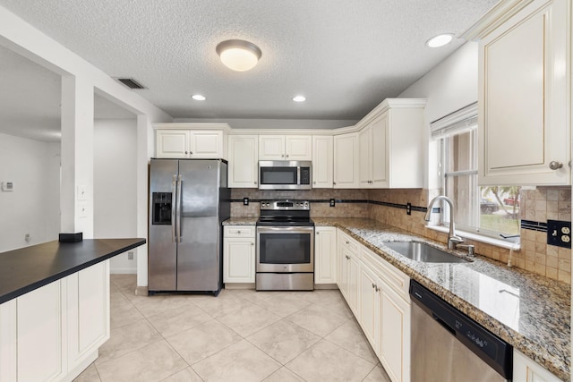 kitchen with decorative backsplash, stone countertops, stainless steel appliances, and sink