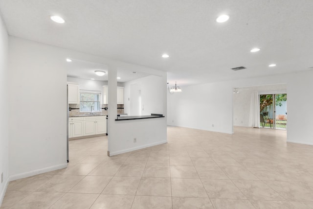 kitchen featuring white cabinets, light tile patterned floors, a chandelier, and sink