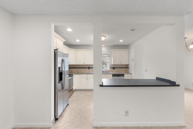 kitchen featuring backsplash, kitchen peninsula, a textured ceiling, light tile patterned flooring, and appliances with stainless steel finishes