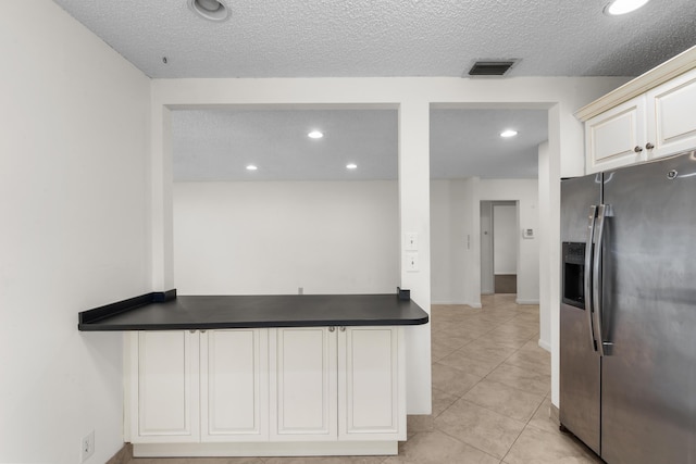 kitchen with a textured ceiling, light tile patterned floors, and stainless steel refrigerator with ice dispenser