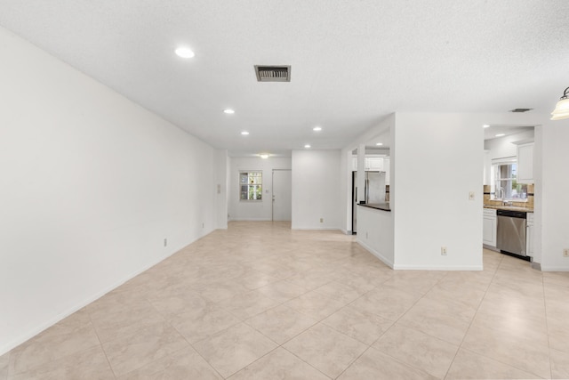 unfurnished living room featuring plenty of natural light, a textured ceiling, and sink