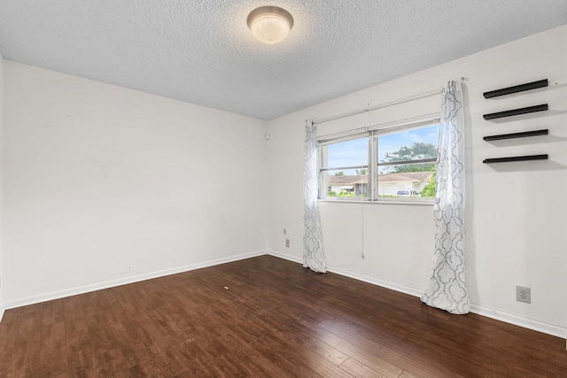 spare room featuring a textured ceiling and dark hardwood / wood-style flooring