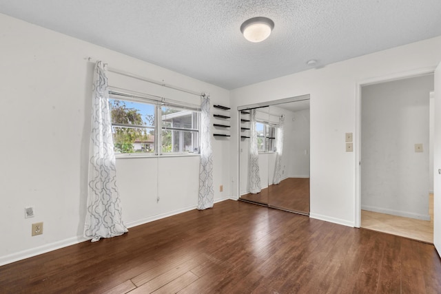 unfurnished bedroom featuring dark hardwood / wood-style floors, a textured ceiling, and a closet