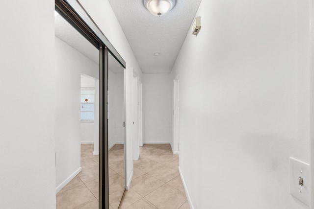 corridor with light tile patterned flooring and a textured ceiling