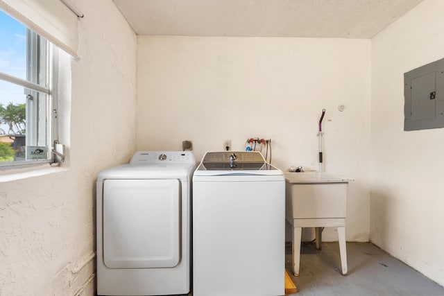 clothes washing area featuring a textured ceiling, washing machine and dryer, sink, and electric panel